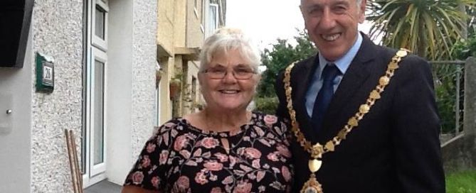 a man with a mayor official chain stands next to a woman