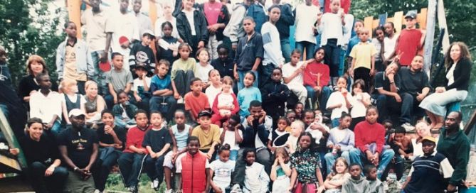 a large group of young people and a few adults on a big piece of play equipment, which can't be seen