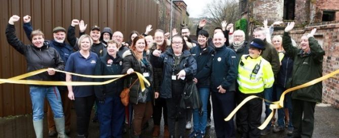 a lot of people at Middleport Matters cutting a ribbon with their hands in the air